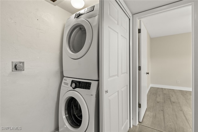 clothes washing area featuring light hardwood / wood-style flooring and stacked washer / dryer