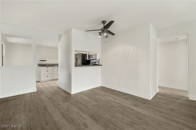 unfurnished living room featuring ceiling fan and dark hardwood / wood-style floors