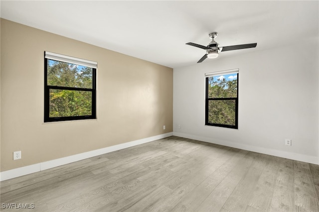 spare room with light wood-type flooring, ceiling fan, and a healthy amount of sunlight