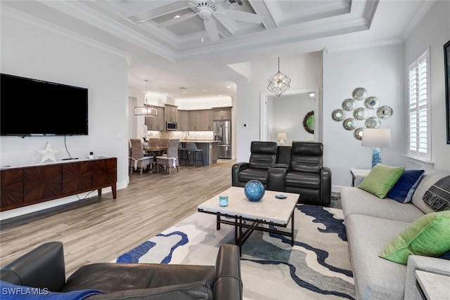 living room with light hardwood / wood-style floors, coffered ceiling, ceiling fan with notable chandelier, beamed ceiling, and ornamental molding