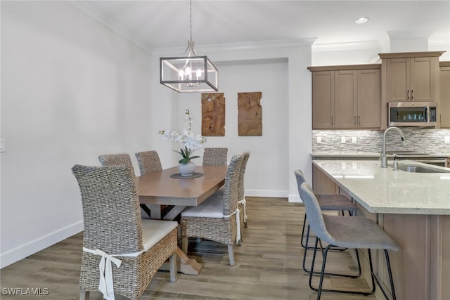 dining area with a notable chandelier, crown molding, dark hardwood / wood-style floors, and sink