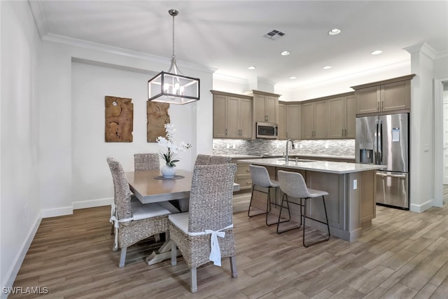 dining space featuring wood-type flooring, ornamental molding, sink, and a notable chandelier