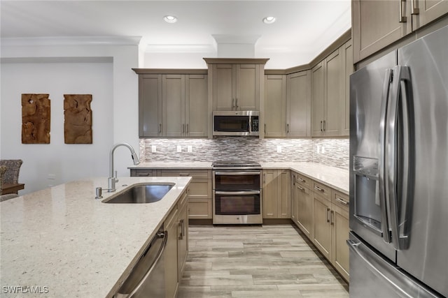 kitchen with ornamental molding, sink, light hardwood / wood-style flooring, stainless steel appliances, and light stone countertops