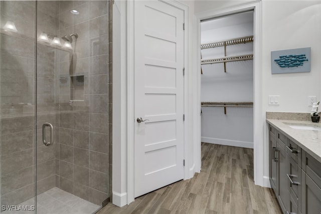 bathroom with a shower with door, hardwood / wood-style floors, and vanity