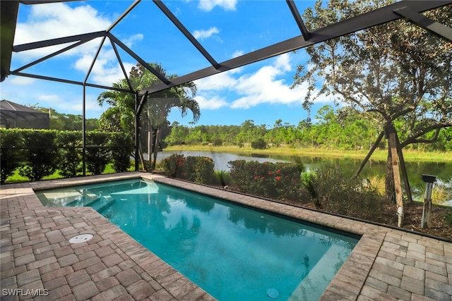 view of pool with glass enclosure, a water view, and a patio area