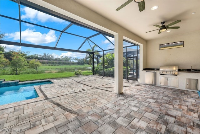 view of patio with a lanai, an outdoor kitchen, a grill, sink, and ceiling fan