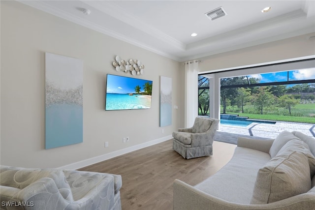 living room featuring hardwood / wood-style flooring, a raised ceiling, and crown molding