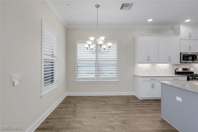 kitchen with white cabinets, appliances with stainless steel finishes, light hardwood / wood-style floors, and decorative light fixtures