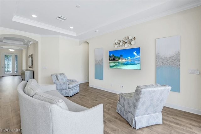 living room featuring a tray ceiling, hardwood / wood-style flooring, and crown molding