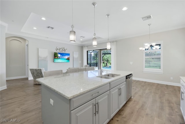 kitchen with pendant lighting, light hardwood / wood-style floors, sink, an island with sink, and stainless steel dishwasher