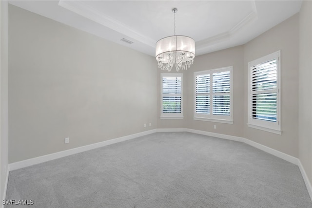 unfurnished room with carpet floors, an inviting chandelier, a tray ceiling, and crown molding