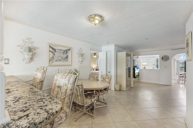 tiled dining space with ornamental molding, ceiling fan, and a textured ceiling