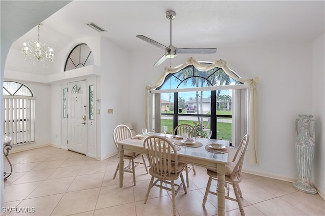 dining area with ceiling fan with notable chandelier, light tile patterned floors, and high vaulted ceiling