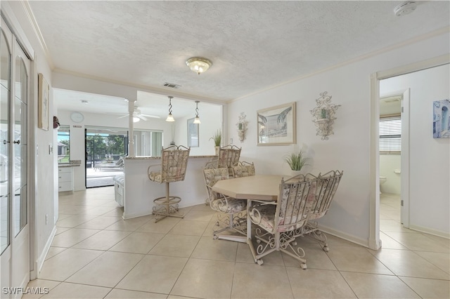 dining space with ornamental molding, a textured ceiling, and light tile patterned floors