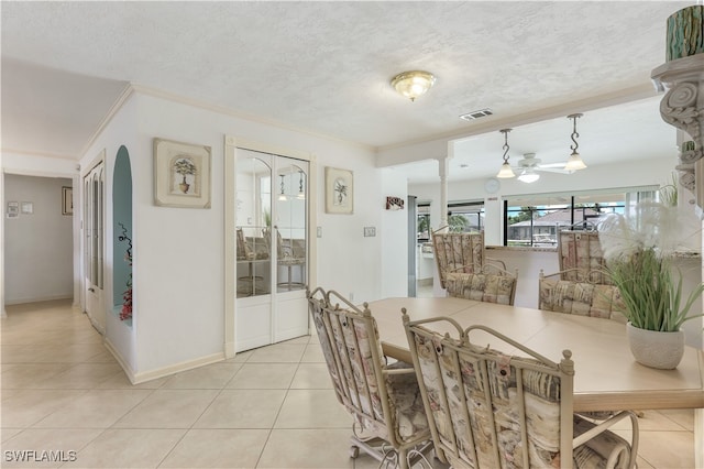 dining space featuring ornamental molding, a textured ceiling, and light tile patterned floors