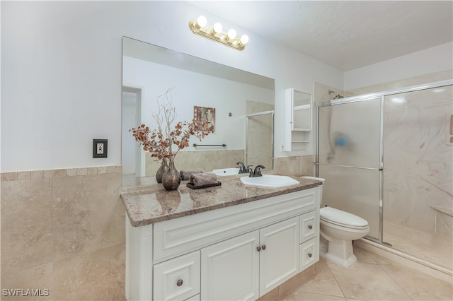 bathroom with tile walls, a shower with shower door, vanity, and toilet