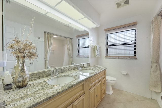 bathroom with vanity, toilet, curtained shower, tile walls, and tile patterned flooring