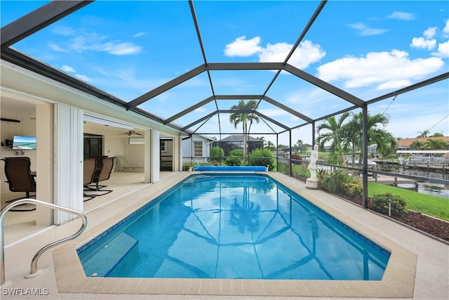 view of pool featuring ceiling fan, a water view, a patio, and a lanai