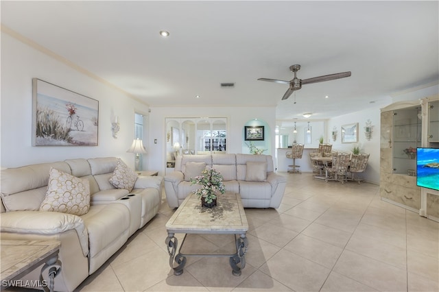 living room featuring light tile patterned floors, ornamental molding, and ceiling fan