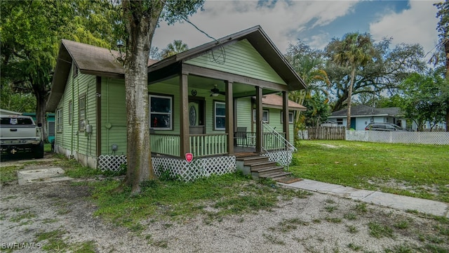 bungalow with a front lawn, covered porch, and ceiling fan