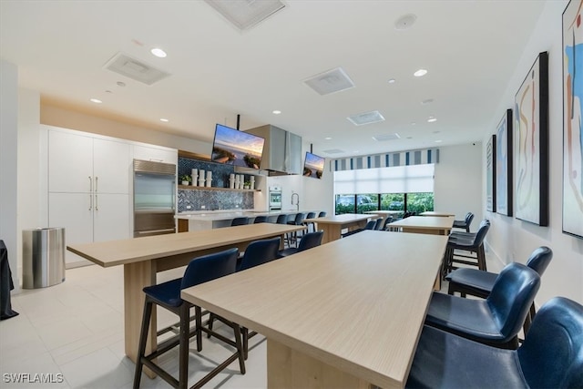 kitchen with tasteful backsplash, a kitchen island, a kitchen breakfast bar, white cabinets, and stainless steel built in fridge