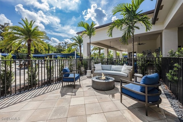 view of patio featuring ceiling fan and an outdoor living space with a fire pit