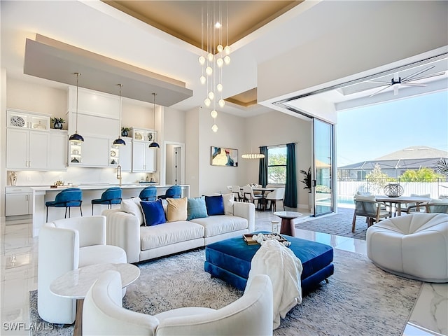 living room with a raised ceiling, a high ceiling, and ceiling fan