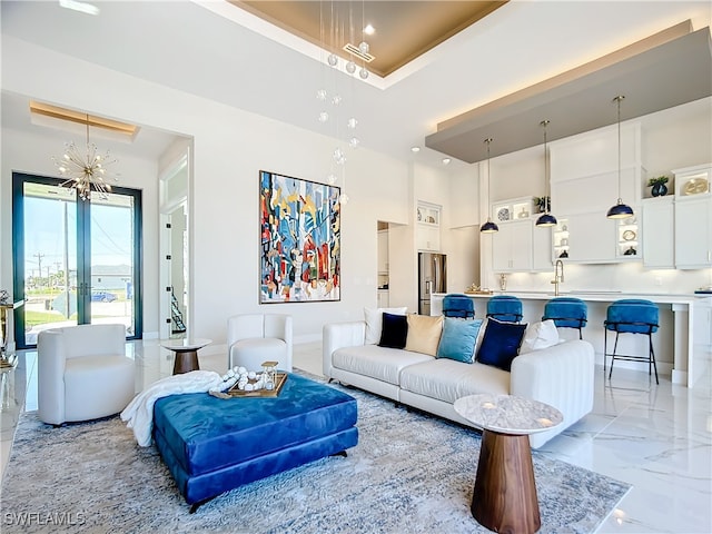 living room featuring an inviting chandelier, sink, and a high ceiling