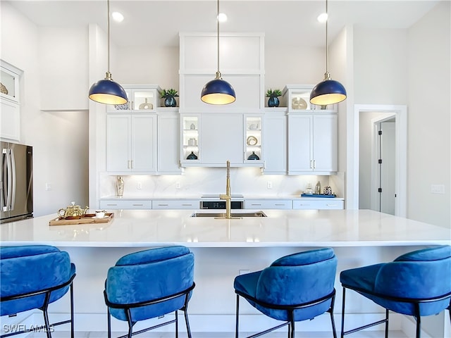 kitchen with stainless steel refrigerator, a large island with sink, and pendant lighting