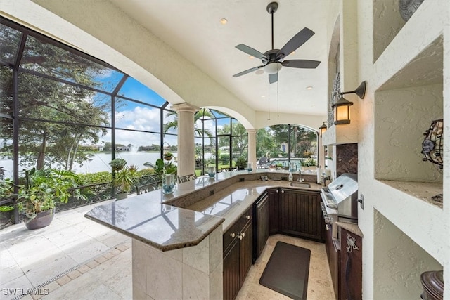 view of patio with glass enclosure, exterior kitchen, ceiling fan, and an outdoor wet bar