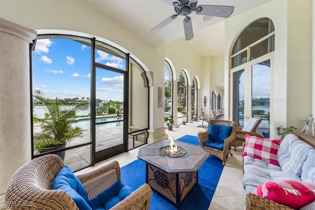 sunroom featuring ceiling fan and a water view