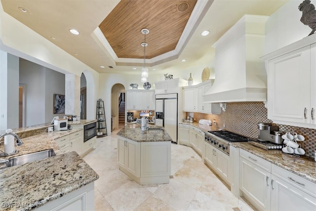 kitchen with stainless steel gas cooktop, decorative backsplash, a center island with sink, and sink