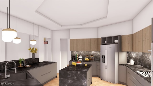 kitchen featuring a tray ceiling, decorative backsplash, stainless steel refrigerator with ice dispenser, and sink