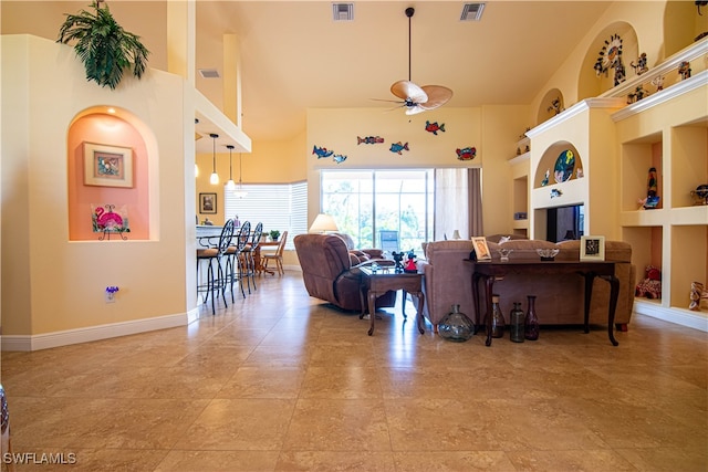 living room featuring a towering ceiling, built in features, and ceiling fan