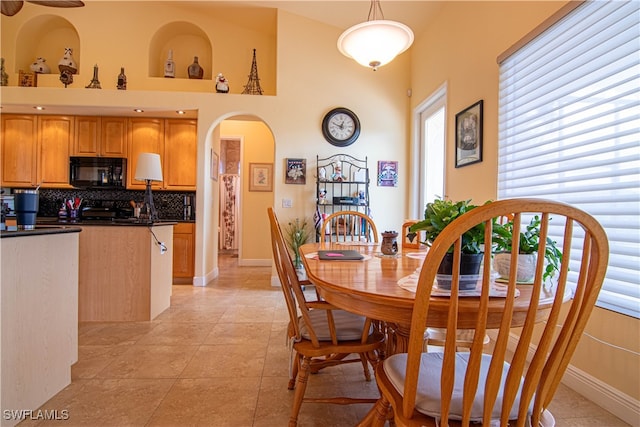 dining area featuring a towering ceiling and light tile patterned flooring