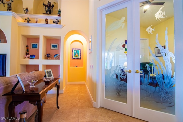 corridor with built in shelves, light tile patterned floors, and french doors