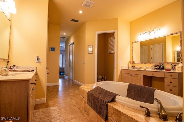 bathroom featuring tile patterned flooring, vanity, toilet, and tiled tub