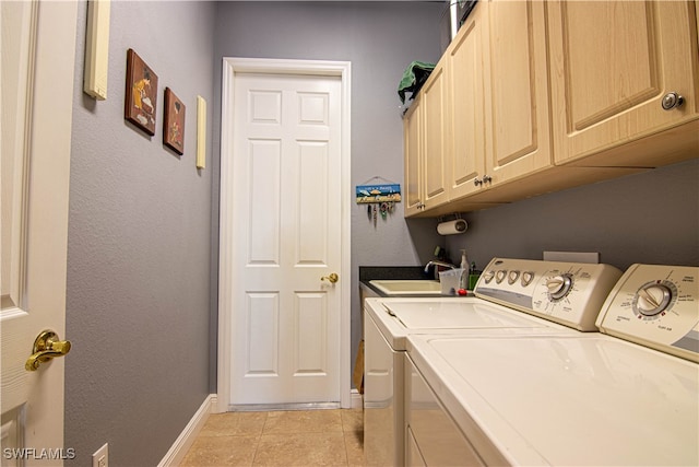 clothes washing area featuring washing machine and clothes dryer, sink, light tile patterned flooring, and cabinets