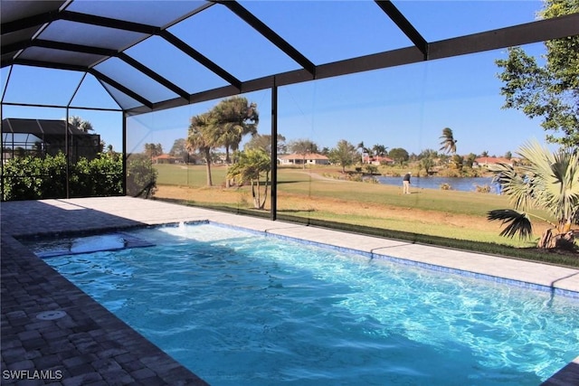 view of swimming pool with pool water feature, a yard, a water view, and glass enclosure