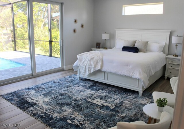 bedroom with access to exterior, hardwood / wood-style flooring, and multiple windows