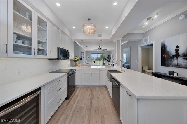 kitchen featuring black appliances, kitchen peninsula, sink, white cabinetry, and beverage cooler