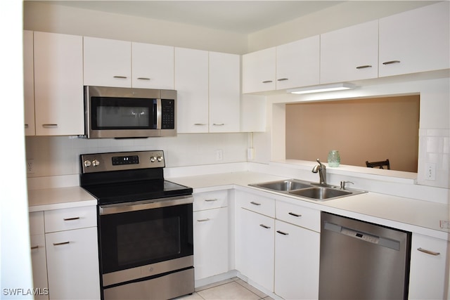 kitchen with white cabinets, appliances with stainless steel finishes, light tile patterned floors, and sink