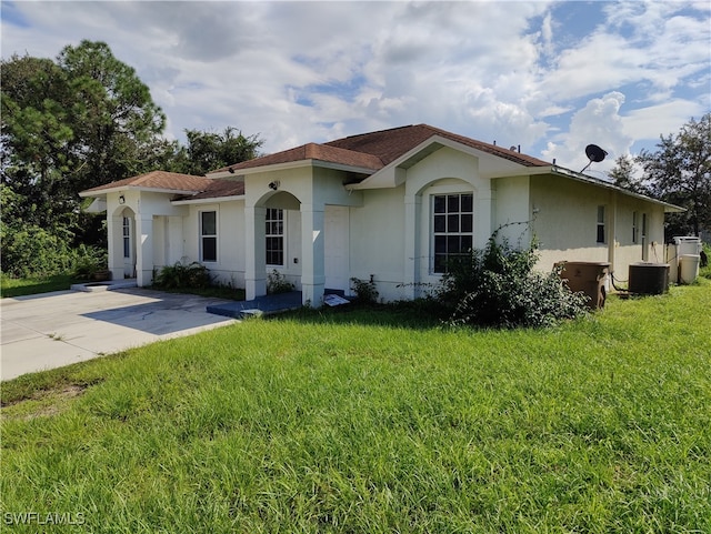 view of front facade featuring a front yard and central air condition unit