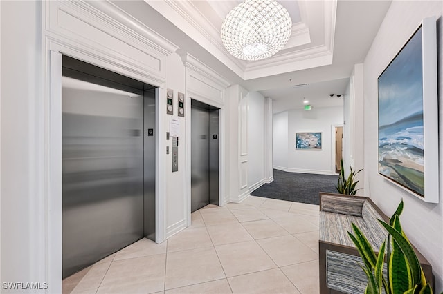 hall featuring a notable chandelier, a raised ceiling, crown molding, and elevator