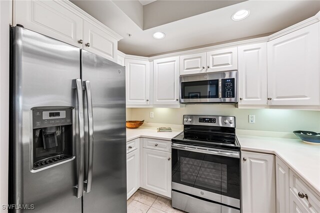 kitchen featuring light tile patterned floors, stainless steel appliances, and white cabinetry