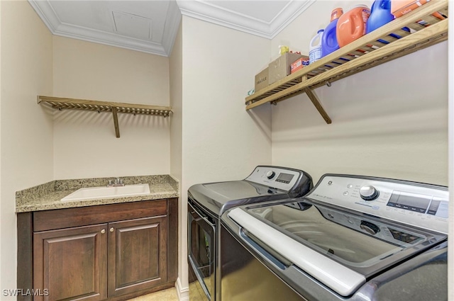 clothes washing area featuring washer and clothes dryer, crown molding, sink, and cabinets