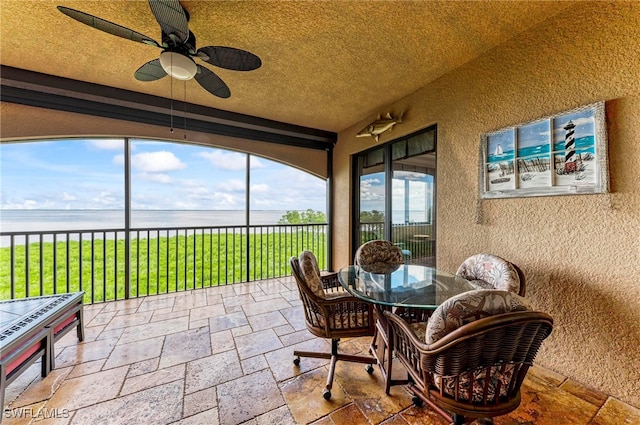 sunroom / solarium with a water view and ceiling fan