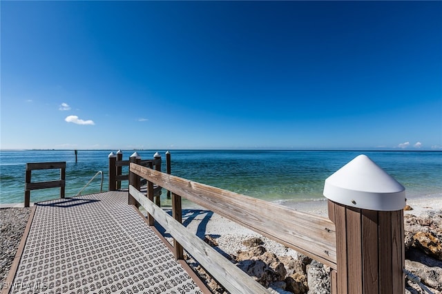 view of dock with a beach view and a water view