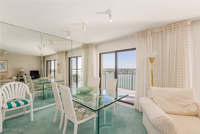 carpeted dining space with a water view and ceiling fan