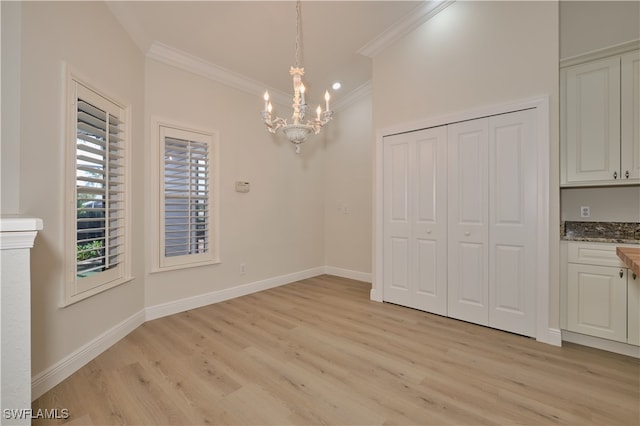 unfurnished dining area with a notable chandelier, ornamental molding, and light wood-type flooring